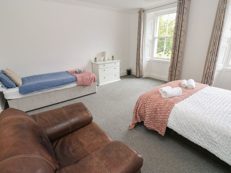 A bedroom with two beds and a dressing table at Georgian Town House in Whitehaven