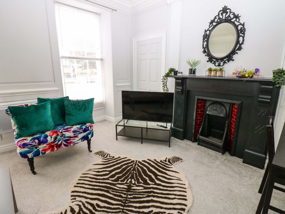 A living room with a sofa and television at Lowther Suite Whitehaven