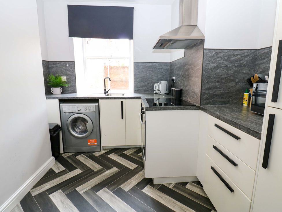 A kitchen with a washing machine and kettle at Lowther Suite in Whitehaven