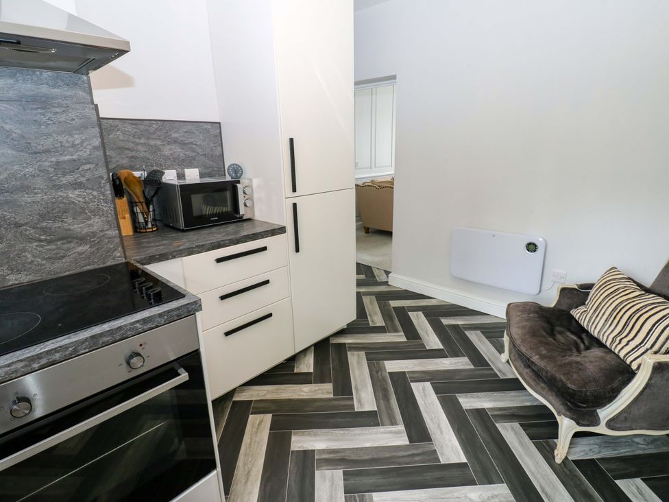 A kitchen with appliances and a chair at Lowther Suite Whitehaven