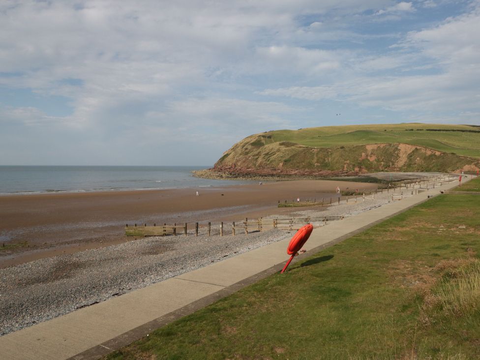 A beach with a cliff and walkway at Lowther Suite in Whitehaven