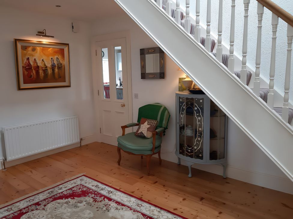 A hallway with a chair and a display cabinet at Moynish Mor Mulranny in MULRANNY