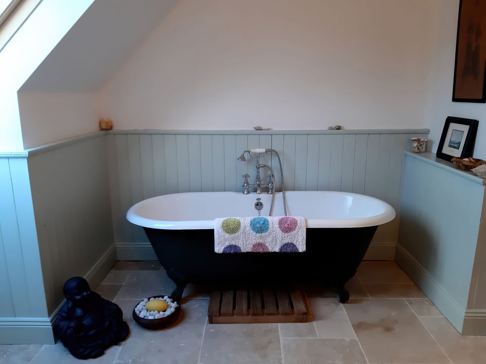 A bathroom with a bathtub and a Buddha statue at Moynish Mor Mulranny in MULRANNY