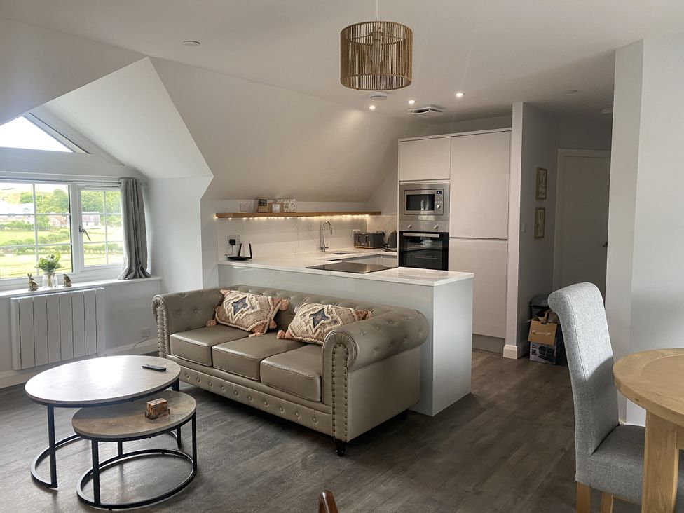 A living room and kitchen with a sofa and countertop at The Gatekeepers Cottage - Skerry Vore near Bryn Pydew