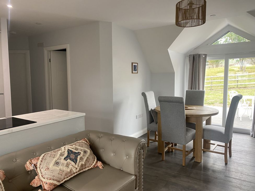 A dining room with a table and chairs at The Gatekeepers Cottage - Skerry Vore, Bryn Pydew near Llandudno Junction