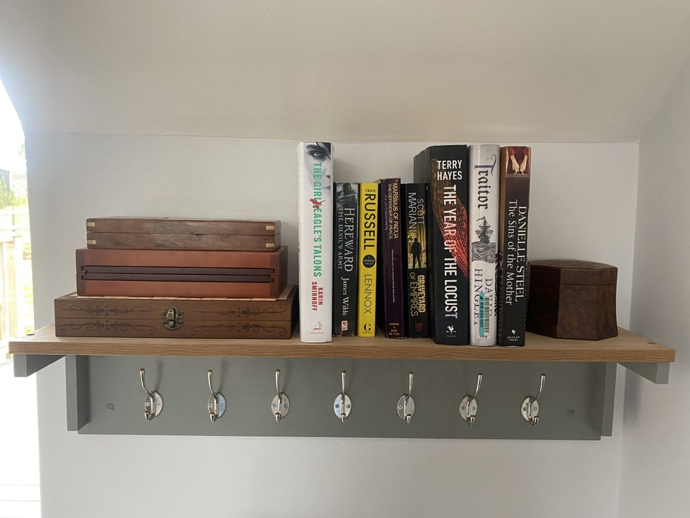 A shelf with books and wooden boxes at The Gatekeepers Cottage - Skerry Vore in Bryn Pydew near Llandudno Junction