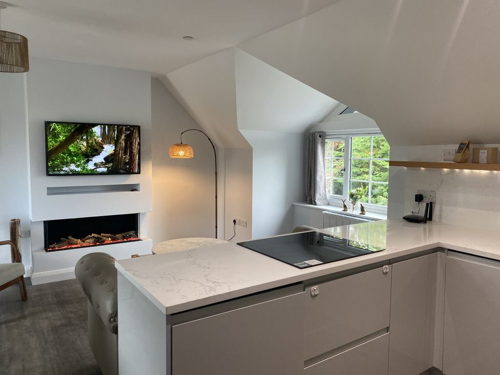 A kitchen with a television, fireplace, and kitchen island at The Gatekeepers Cottage - Skerry Vore near Bryn Pydew