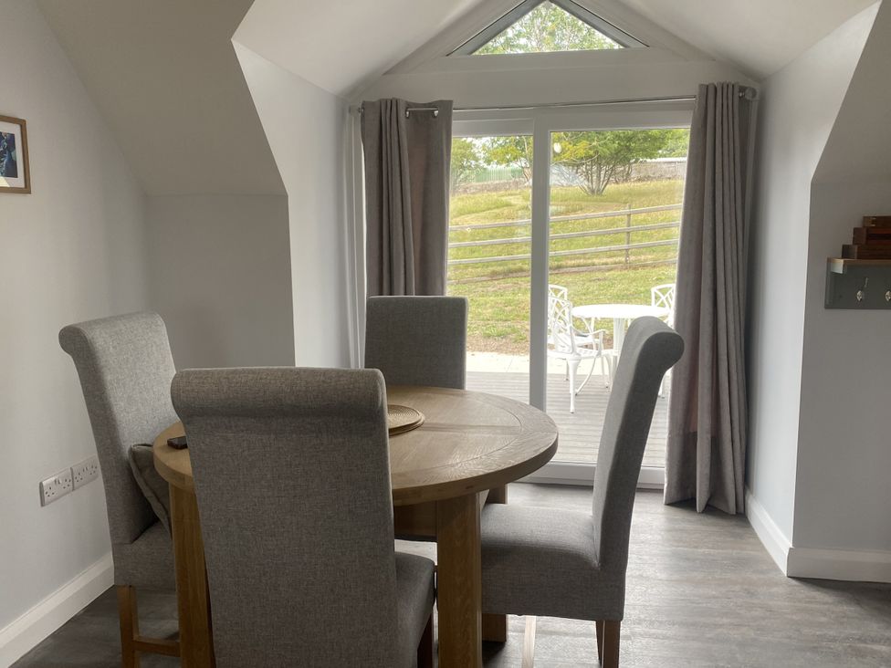A dining room with a table and chairs at The Gatekeepers Cottage - Skerry Vore in Bryn Pydew near Llandudno Junction