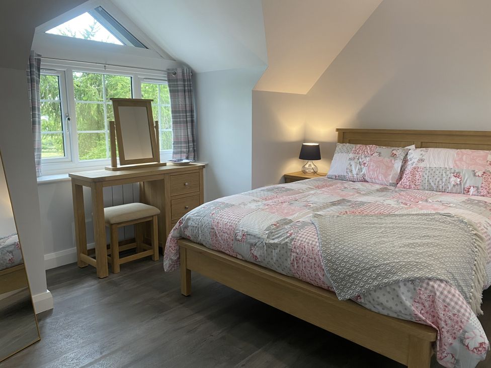 A bedroom with a bed, table, and window at The Gatekeepers Cottage - Skerry Vore in Bryn Pydew near Llandudno Junction