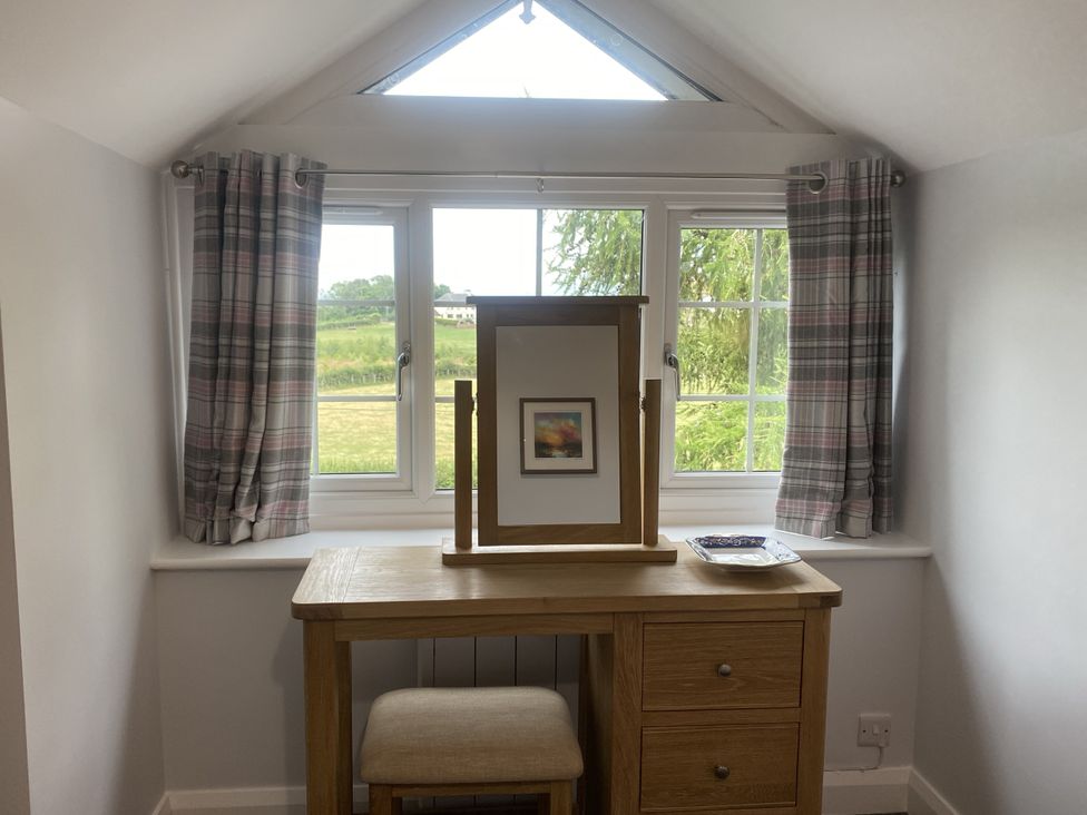 A bedroom with a mirror and table by a window at The Gatekeepers Cottage - Skerry Vore Bryn Pydew near Llandudno Junction