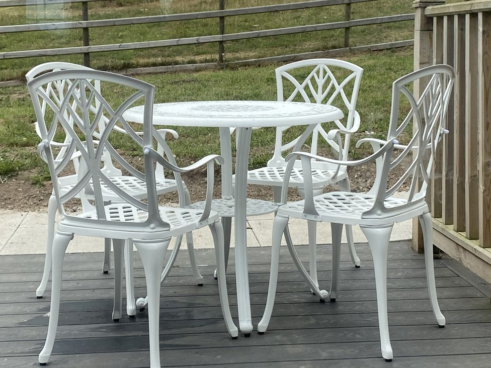 Outdoor seating area with a table and chairs at The Gatekeepers Cottage - Skerry Vore, Bryn Pydew near Llandudno Junction