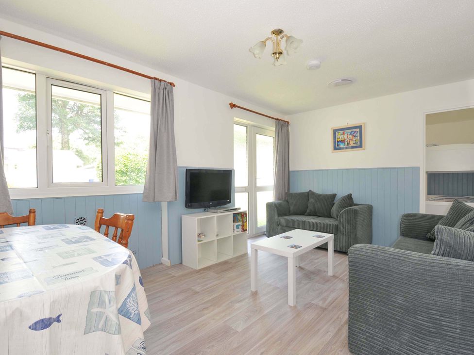A living room with a table and chairs and a tv at 4 Rosecraddoc Lodge Holiday Bungalows in Liskeard