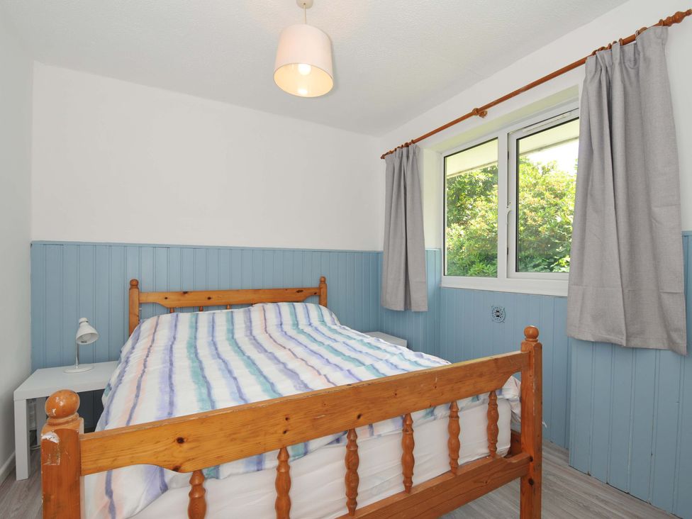 A bedroom with a wooden bed and bedside table at 4 Rosecraddoc Lodge Holiday Bungalows Liskeard