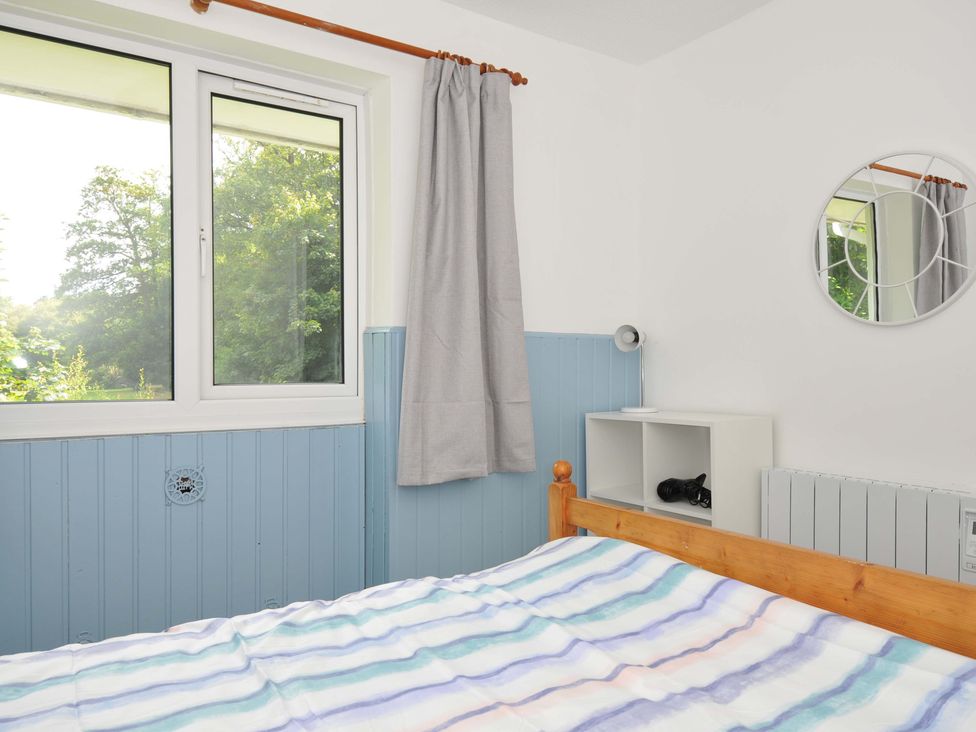 A bedroom with a bed and window at 4 Rosecraddoc Lodge Holiday Bungalows in Liskeard
