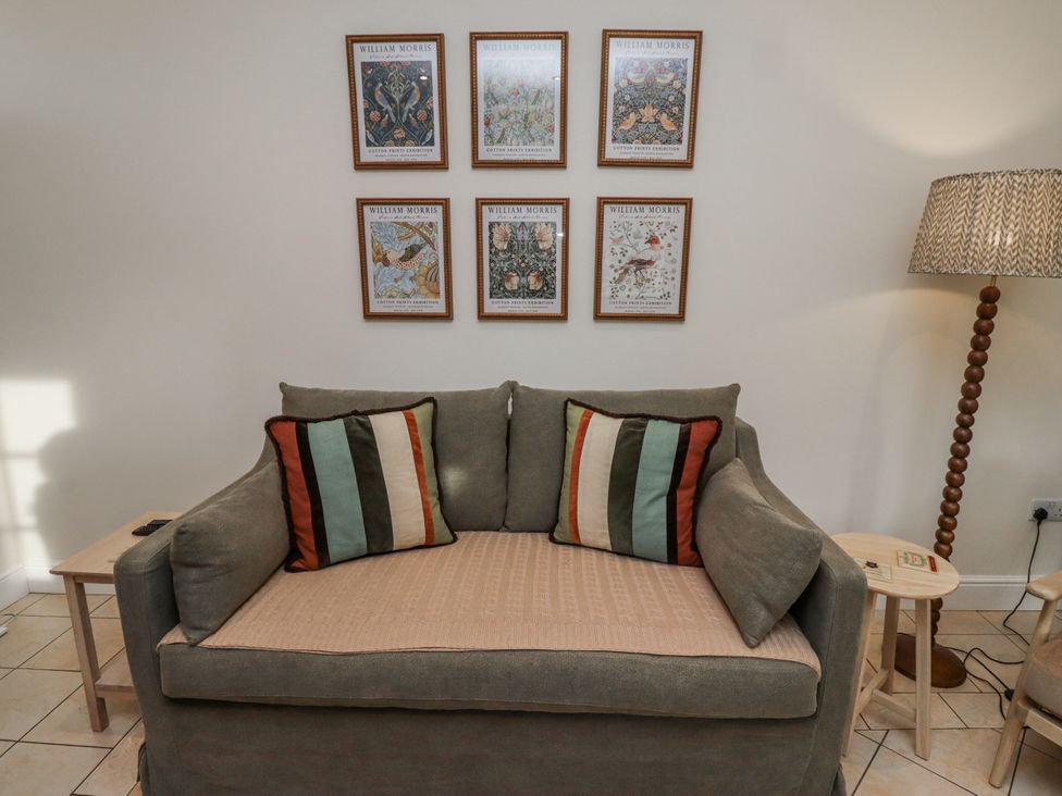 A living room with a couch and wall art at Watermill Cottage in North Charlton