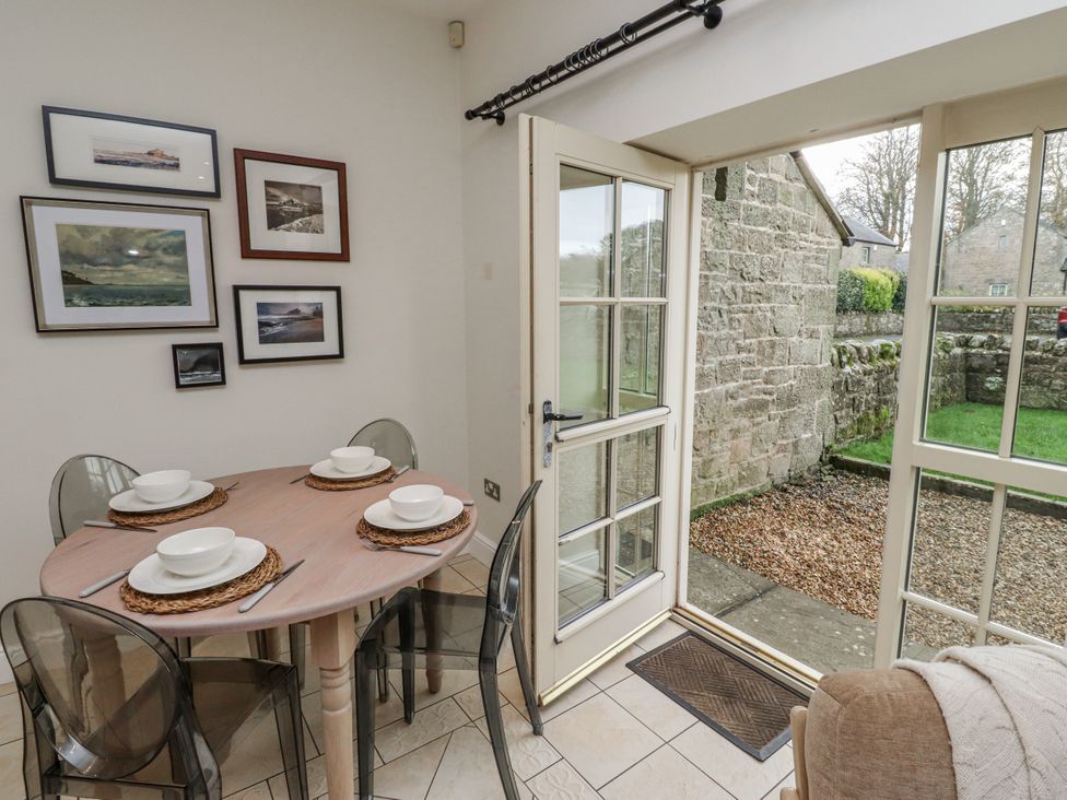 A dining room with a table set for meals at Watermill Cottage in North Charlton