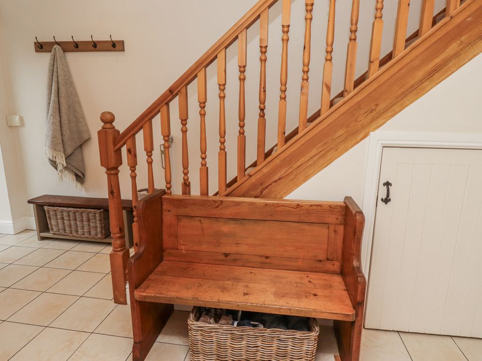 A hallway with a wooden bench and staircase at Watermill Cottage North Charlton