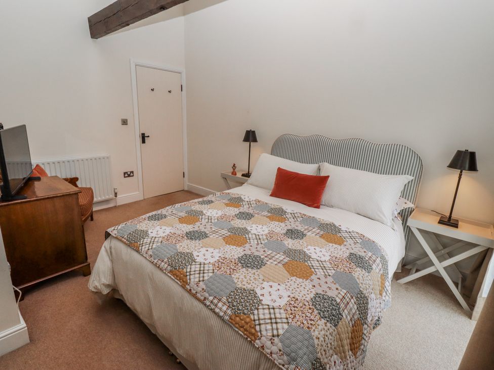 A bedroom with a bed and television at Watermill Cottage in North Charlton