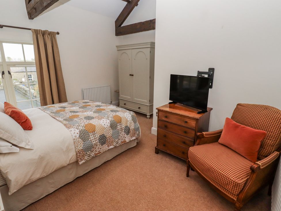 A bedroom with a bed and television at Watermill Cottage North Charlton