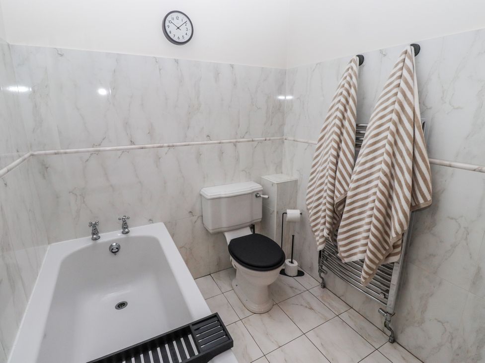 A bathroom with a bathtub and toilet at Watermill Cottage North Charlton