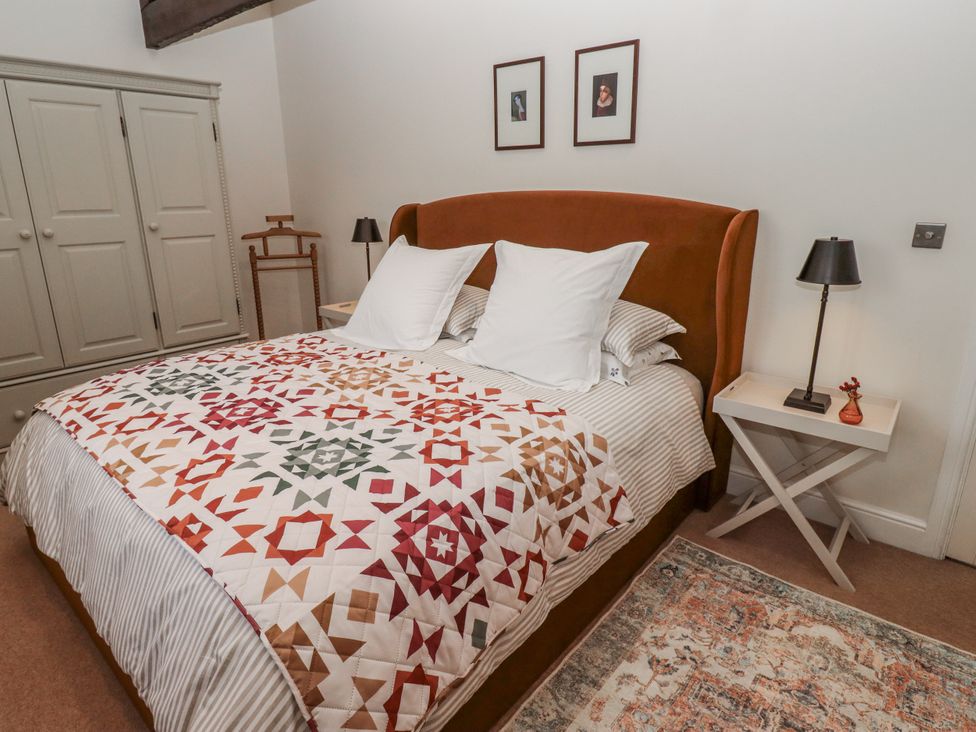 A bedroom with a large bed and wardrobe at Watermill Cottage in North Charlton