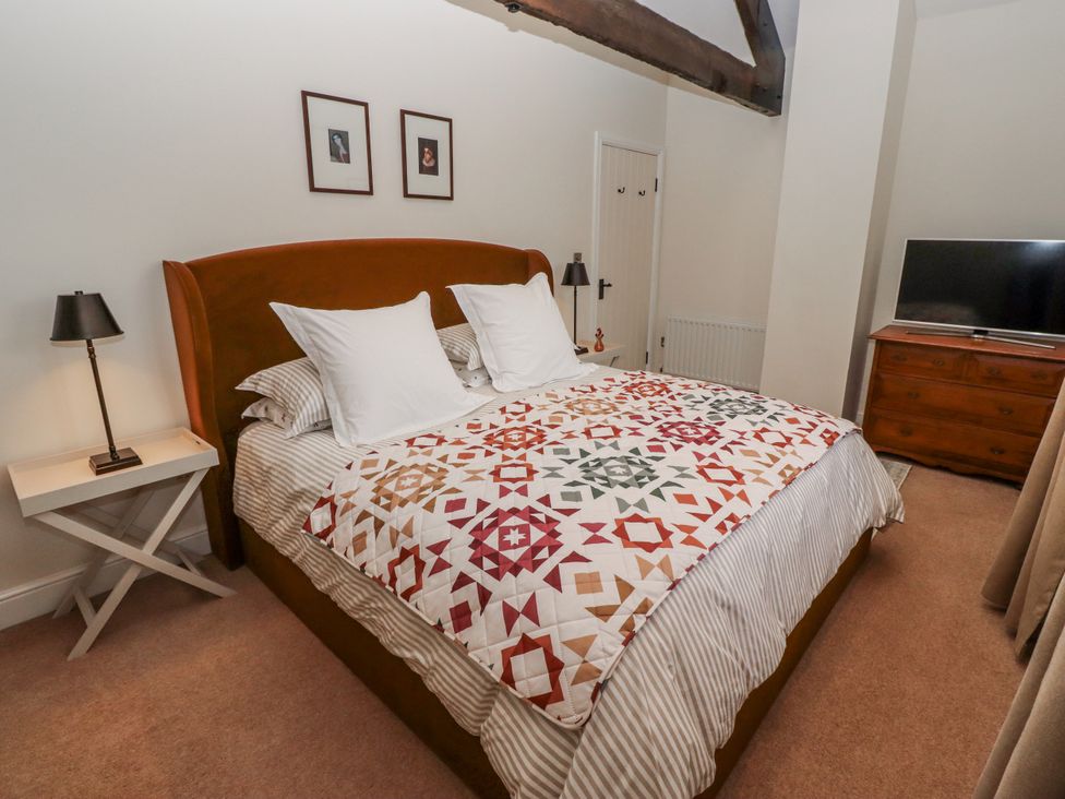 A bedroom with a bed, bedside lamp and television at Watermill Cottage in North Charlton