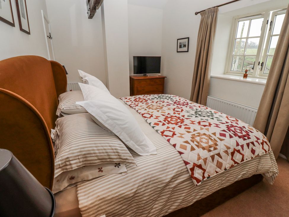 A bedroom with a bed and television at Watermill Cottage in North Charlton