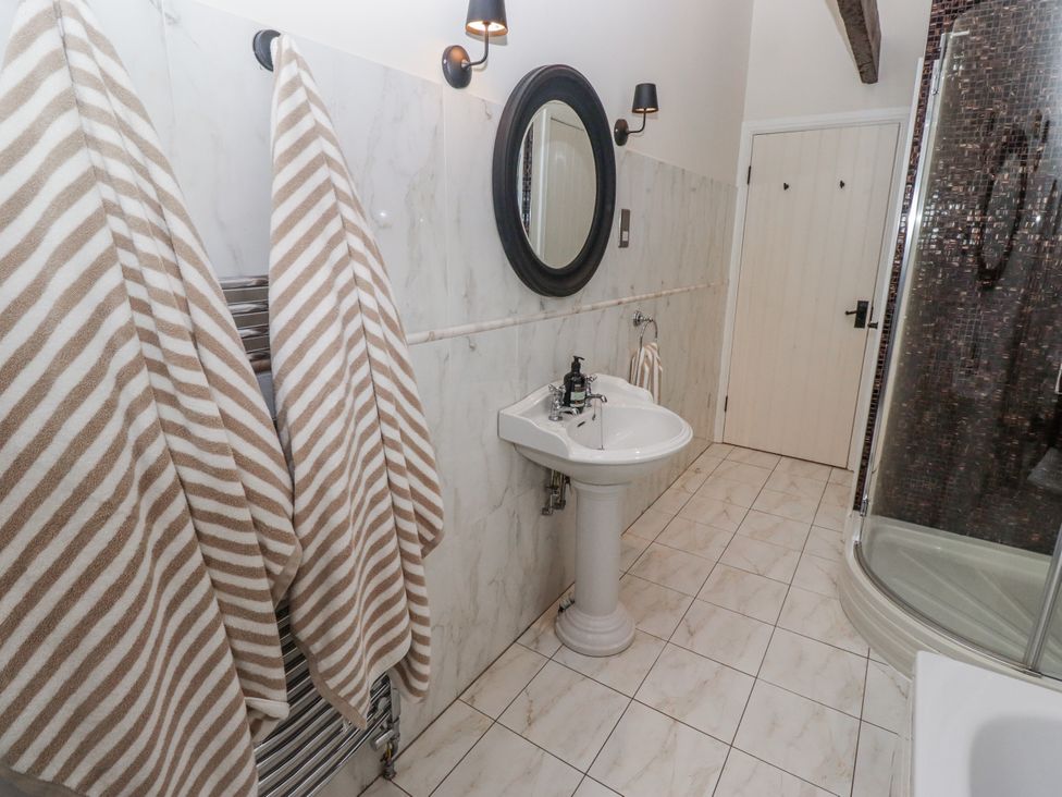 A bathroom with a sink, shower, and towels at Watermill Cottage in North Charlton