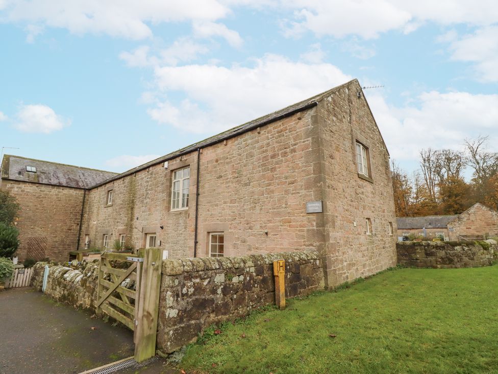 A stone building with windows and a gate at Watermill Cottage in North Charlton