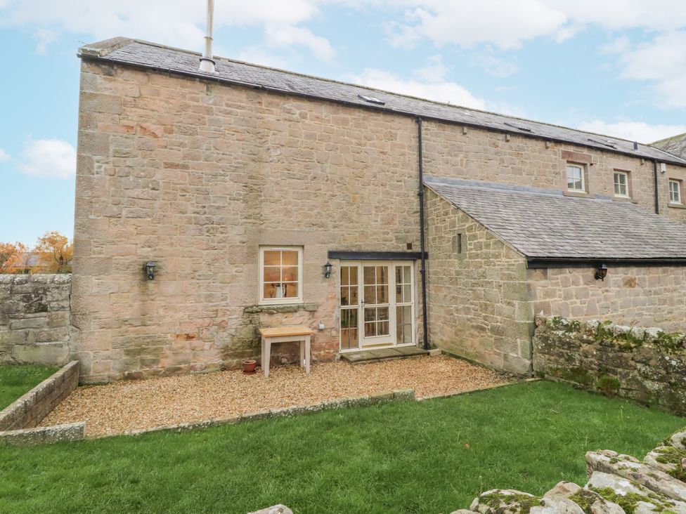 An outdoor area with a table and gravel at Watermill Cottage in North Charlton