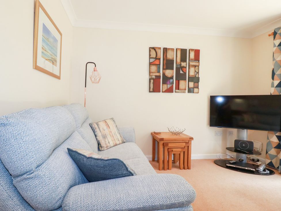 A living room with a sofa and television at Trouts Reach in Falmouth
