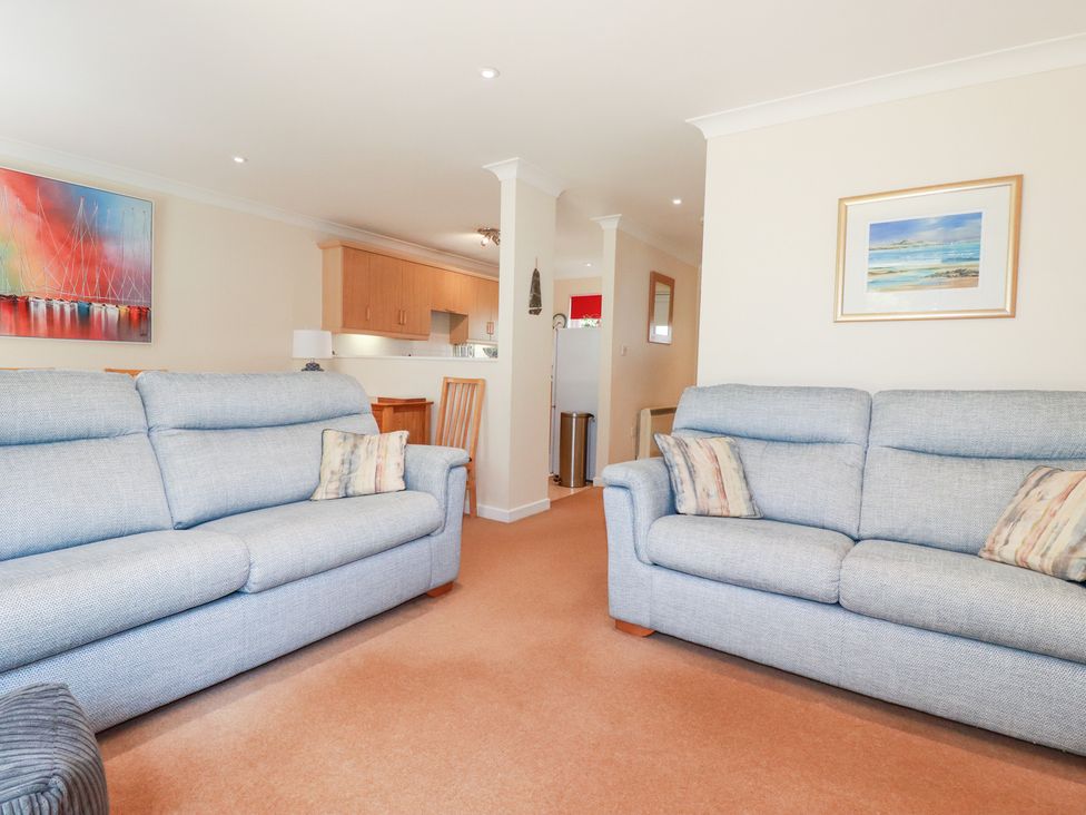 A living room with sofas and dining area at Trouts Reach in Falmouth