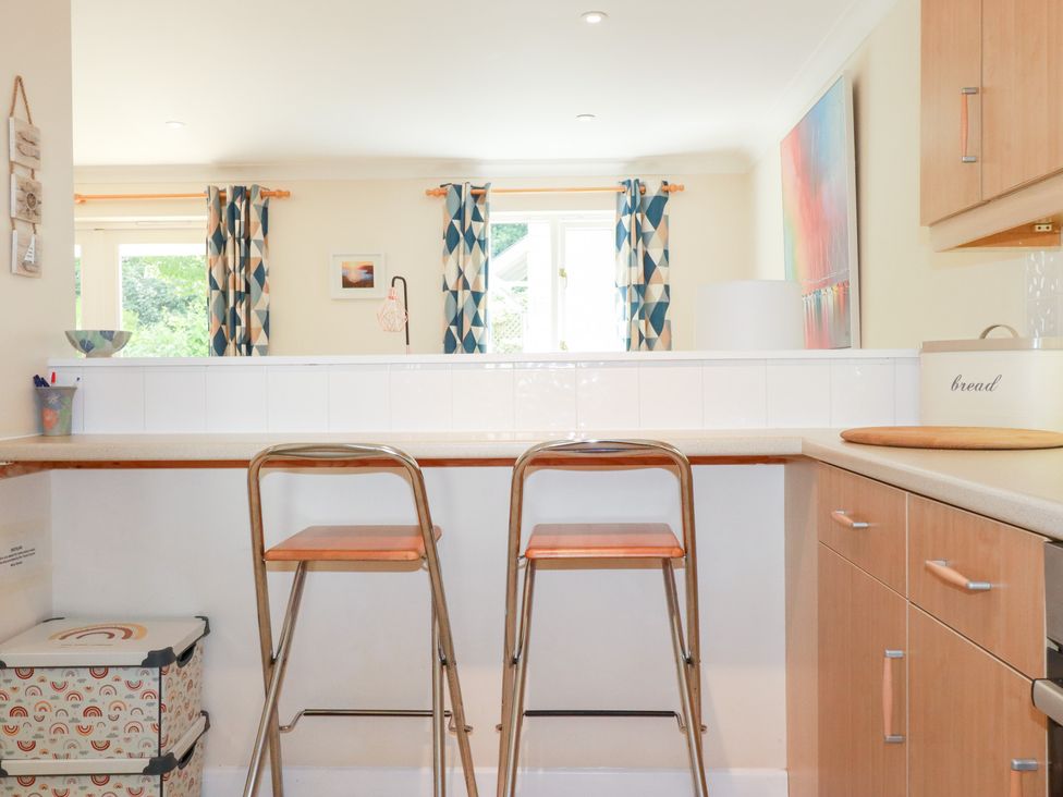 A kitchen with bar stools and a counter at Trouts Reach in Falmouth