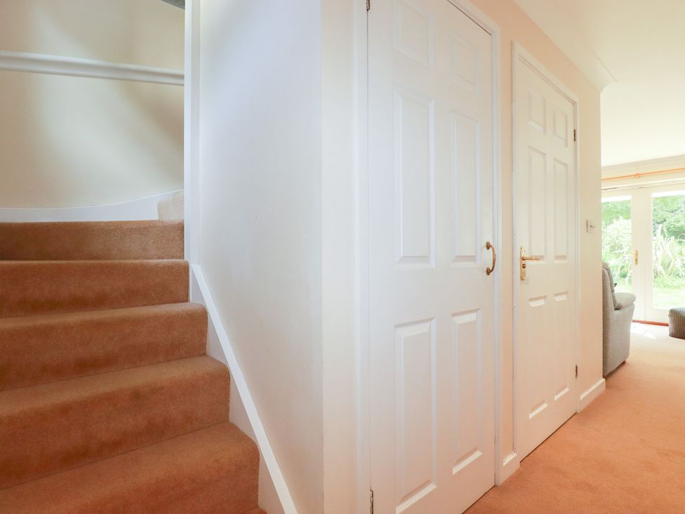 A hallway with stairs and doors at Trouts Reach in Falmouth