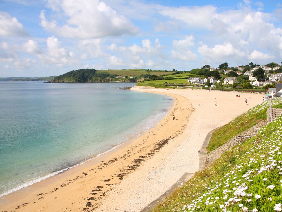 A beach with people walking along the shore at Trouts Reach, Goldenbank near Budock Water