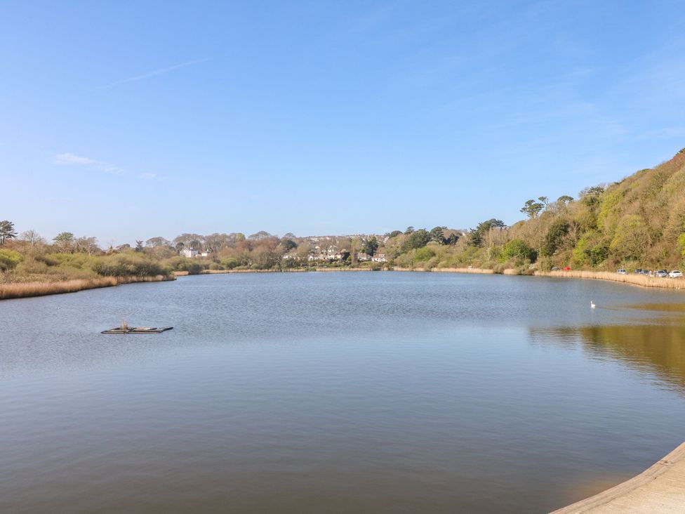 A view of a lake with trees and buildings at Trouts Reach Goldenbank near Budock Water