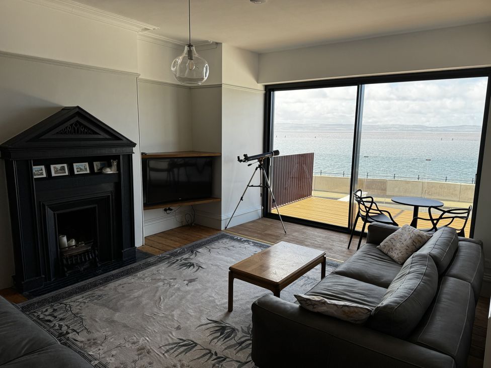 A living room with a fireplace and telescope at Mostyn View in West Kirby