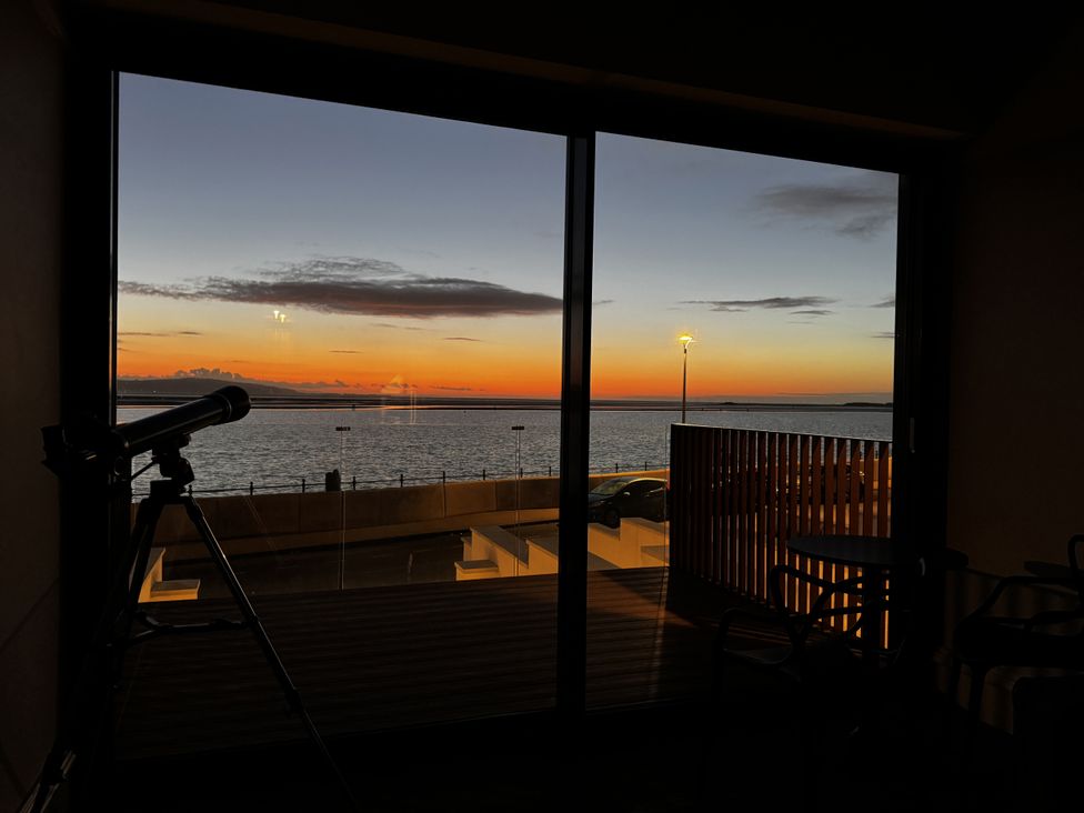 A living room with a telescope and a view of the sea at Mostyn View in West Kirby