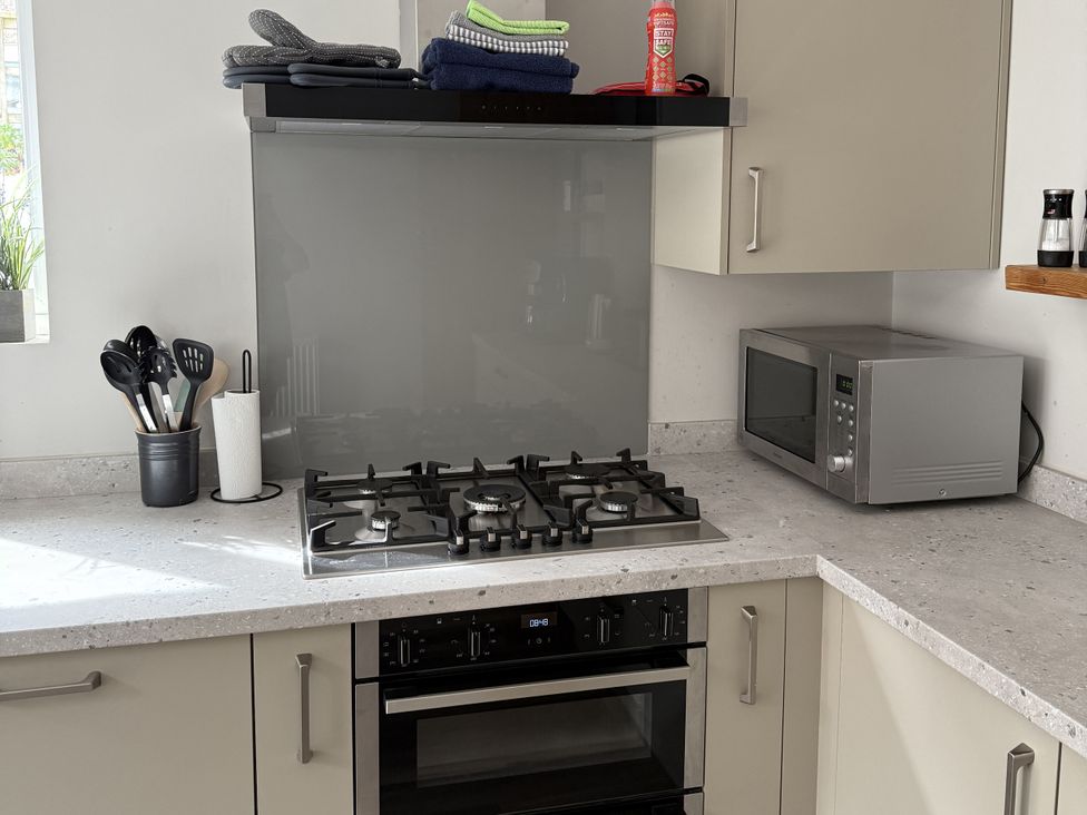 A kitchen with a gas stove and microwave at Mostyn View in West Kirby