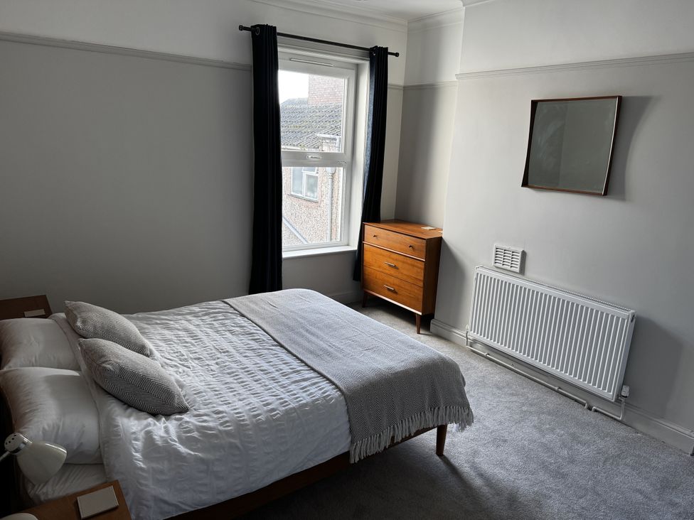 A bedroom with a bed, mirror, and dresser at Mostyn View in West Kirby