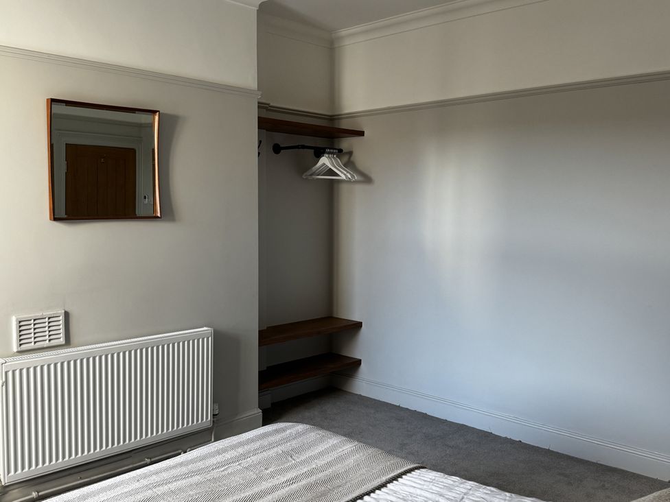 A bedroom with a mirror and shelves at Mostyn View, West Kirby