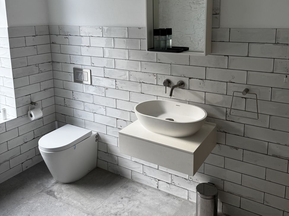 A bathroom with a sink, toilet, and mirror at Mostyn View in West Kirby