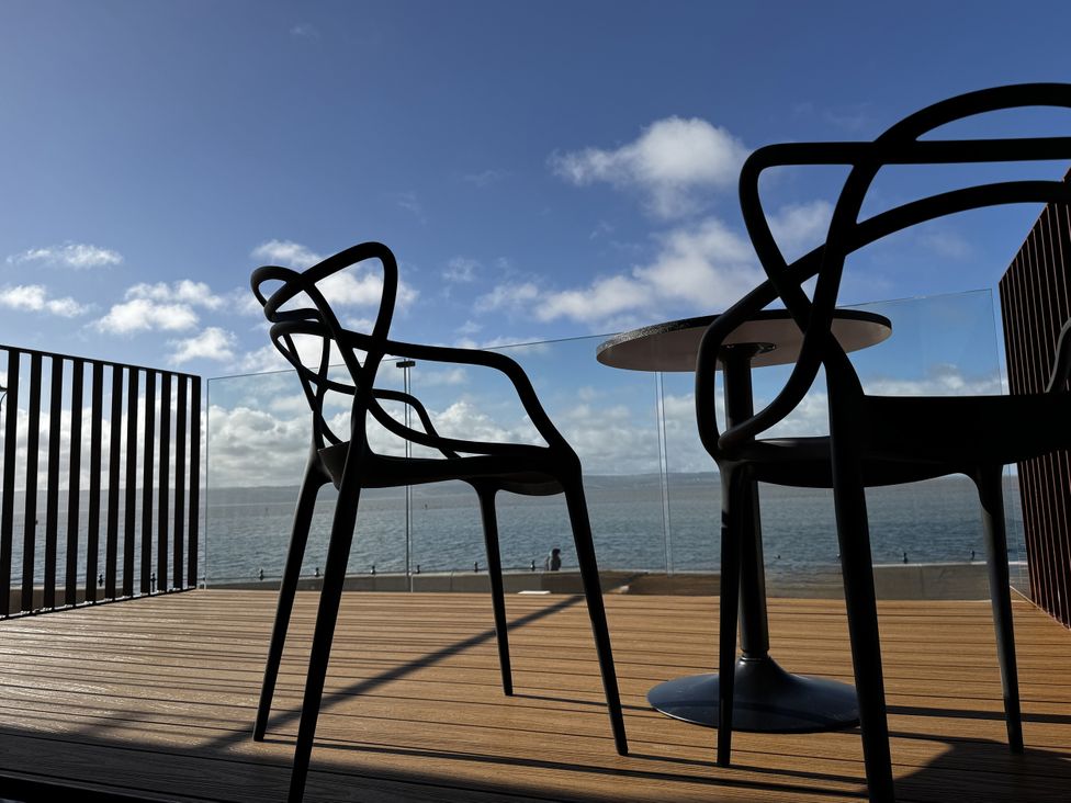 A balcony with chairs and a table overlooking the water at Mostyn View, West Kirby
