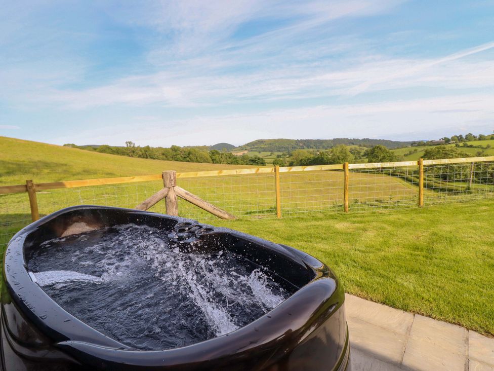 A hot tub with water and a scenic landscape at Defaid Cymreig Oswestry