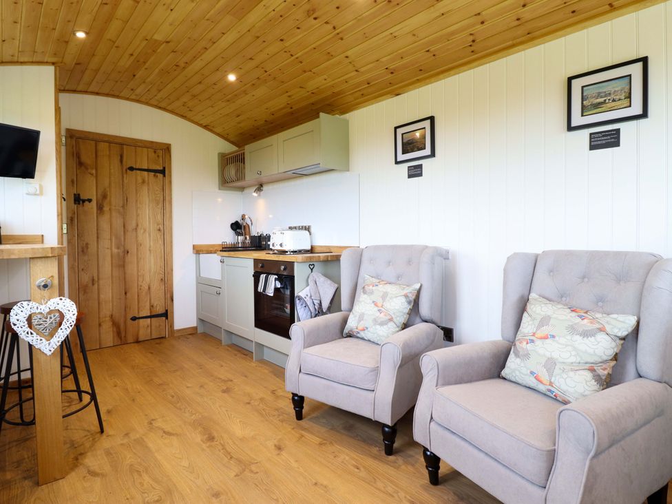 A living room with chairs and kitchen unit at Defaid Cymreig in Oswestry