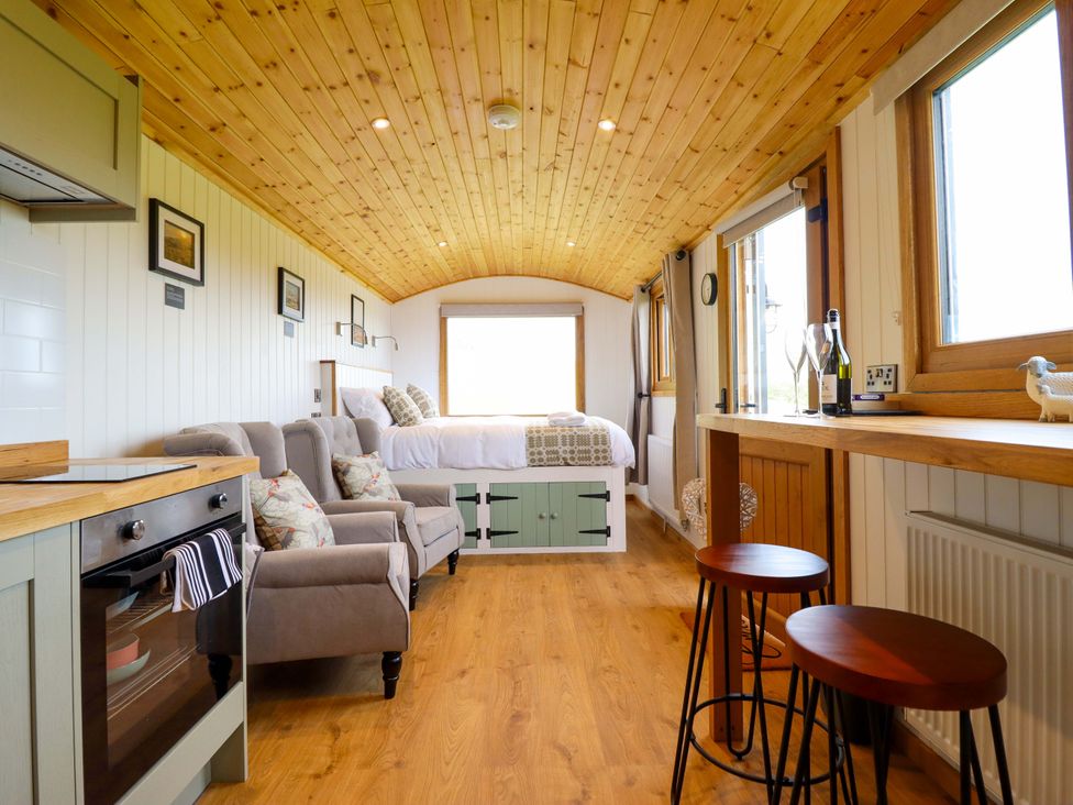 A living room with a kitchen unit and seating area at Defaid Cymreig Oswestry