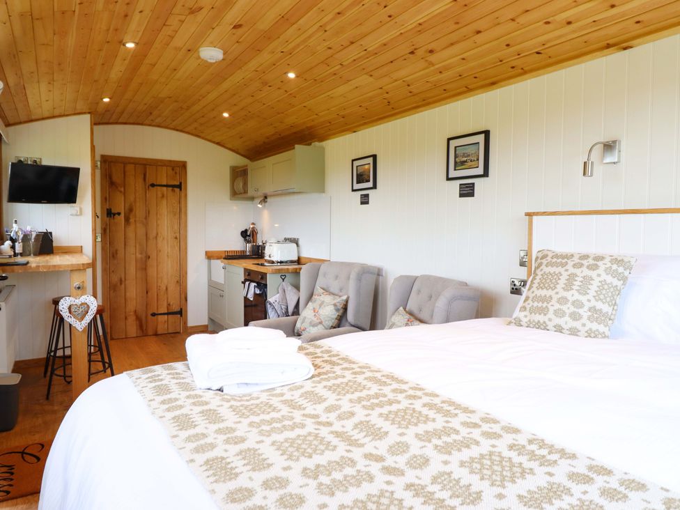A bedroom with a bed and kitchenette at Defaid Cymreig Oswestry