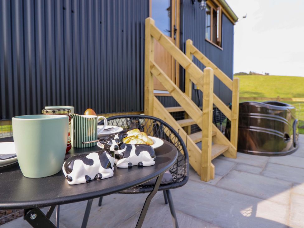 An outdoor seating area with a table and cow figurines at Defaid Cymreig in Oswestry