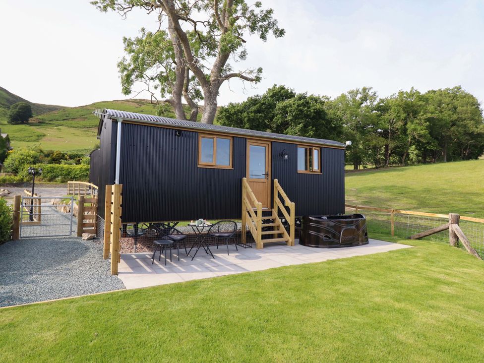 An outdoor area with a tiny house, table and chairs at Defaid Cymreig in Oswestry