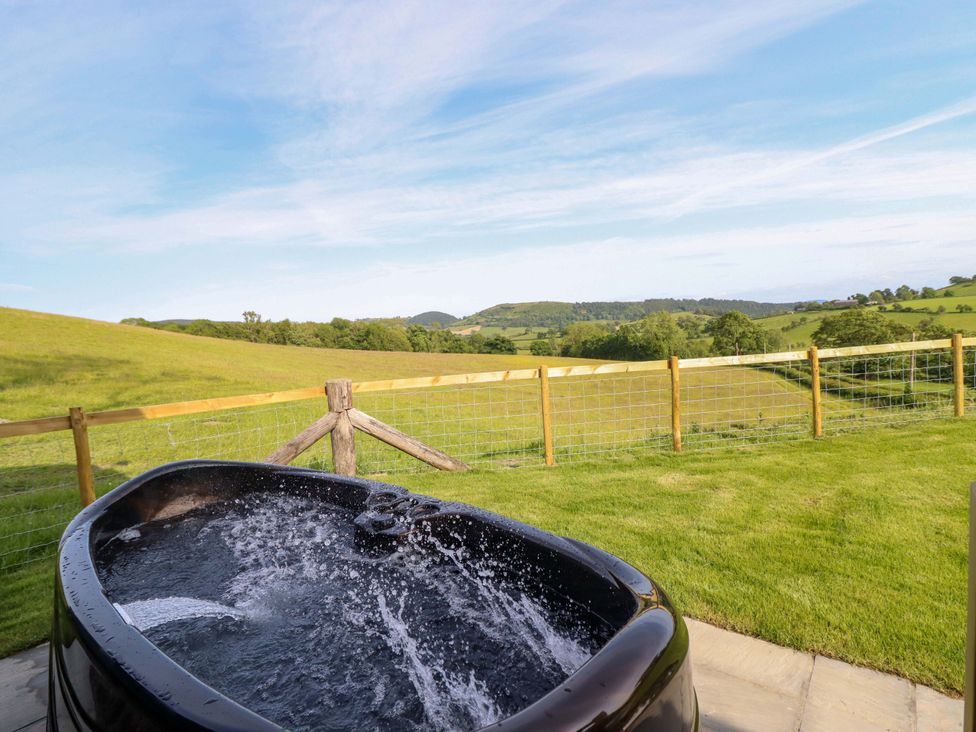 A hot tub with a view of a hillside at Defaid Cymreig Oswestry
